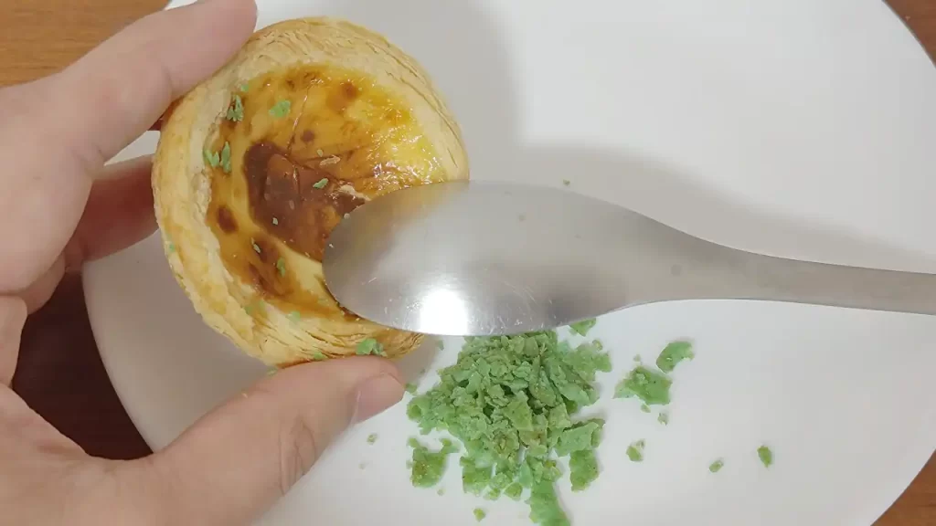 台湾KFC パクチーエッグタルトのパクチードリトスフレークを取っているところ